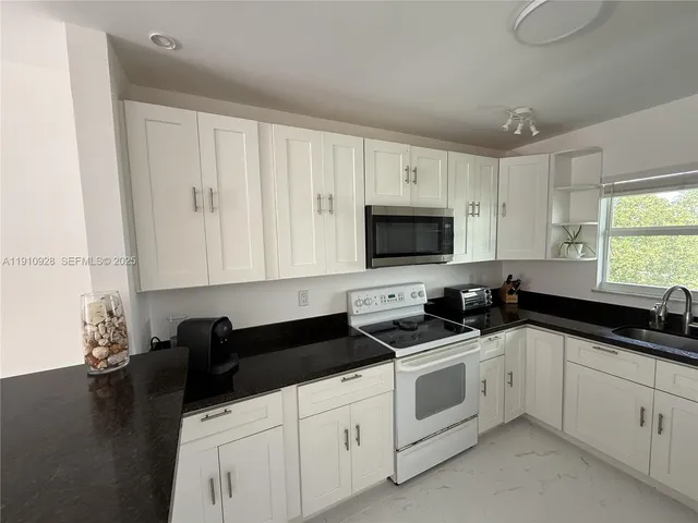 a kitchen with white cabinets and sink