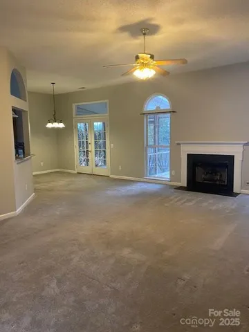 a view of an empty room with a fireplace and a chandelier