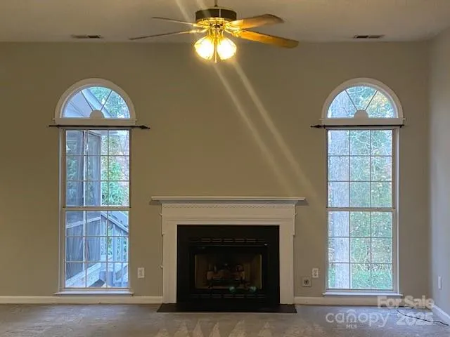 an empty room with windows and fireplace