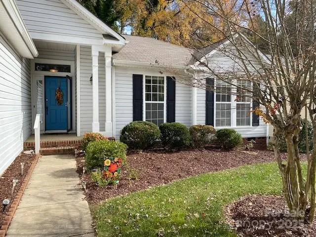 a view of a house with a small yard and large tree