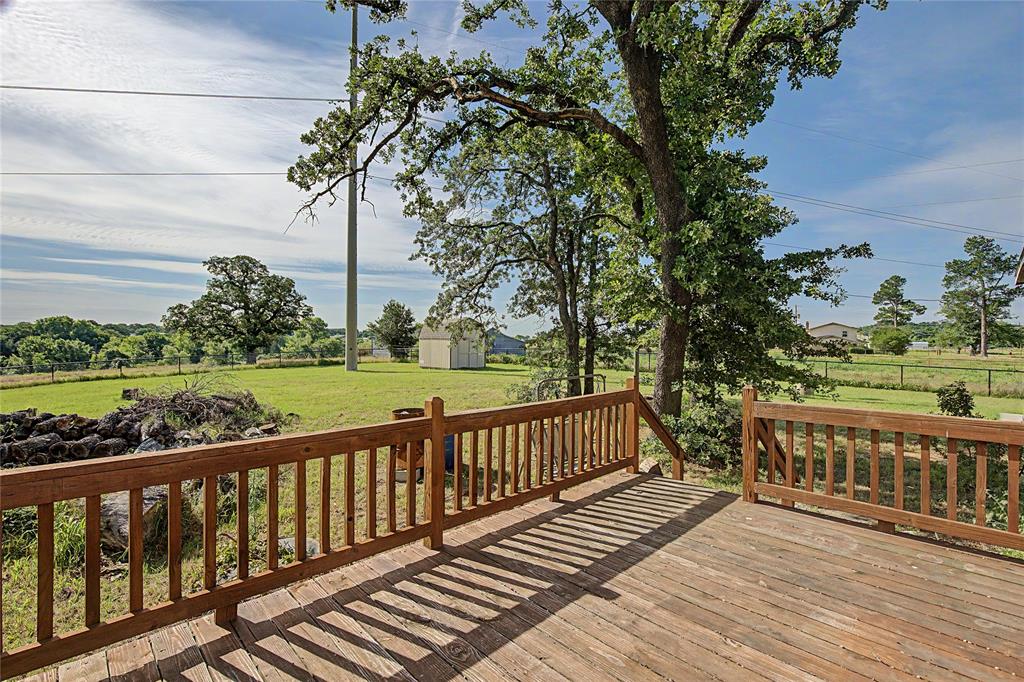177 New Highland Road Springtown, TX 76082 - Photo 31 of 40 Spacious exterior deck with natural wood railing overlooking a green lawn