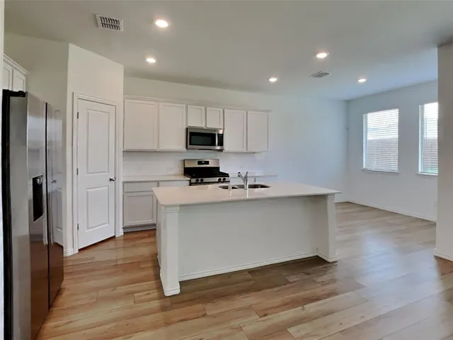 a kitchen with stainless steel appliances a refrigerator and a stove top oven