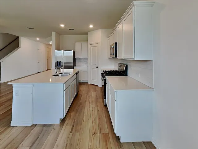 a kitchen with stainless steel appliances a sink stove and wooden floor