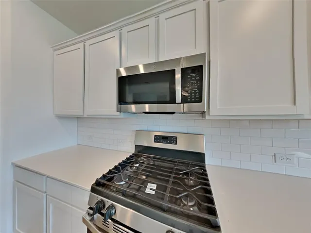 a kitchen with white cabinets and appliances