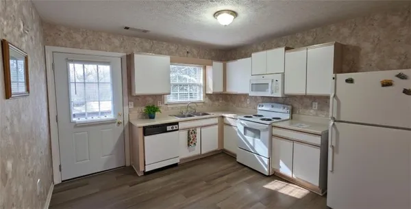 a kitchen with granite countertop white cabinets and white appliances
