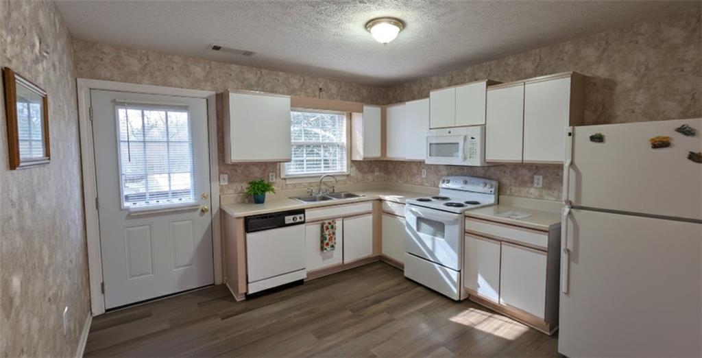 a kitchen with granite countertop white cabinets and white appliances