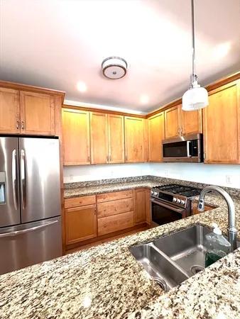 a kitchen with stainless steel appliances granite countertop a stove a sink and a refrigerator