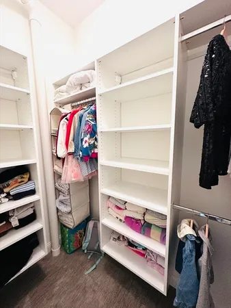 a view of walk in closet with clothes and shoes