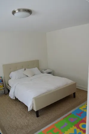 a bedroom with a bed and a lamp on the dresser