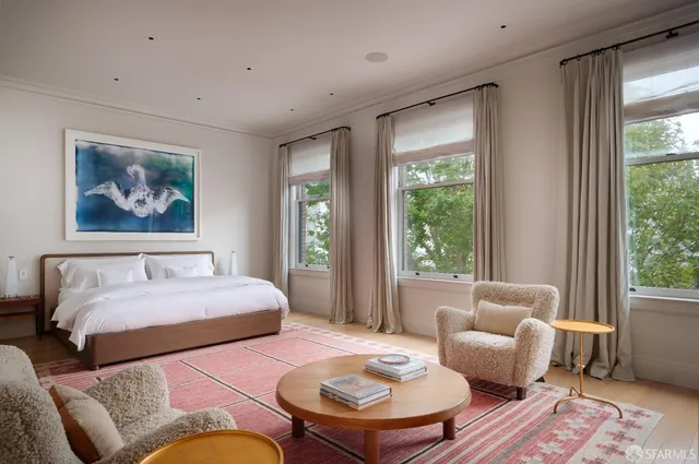 a bedroom with a large bed couch and a large window