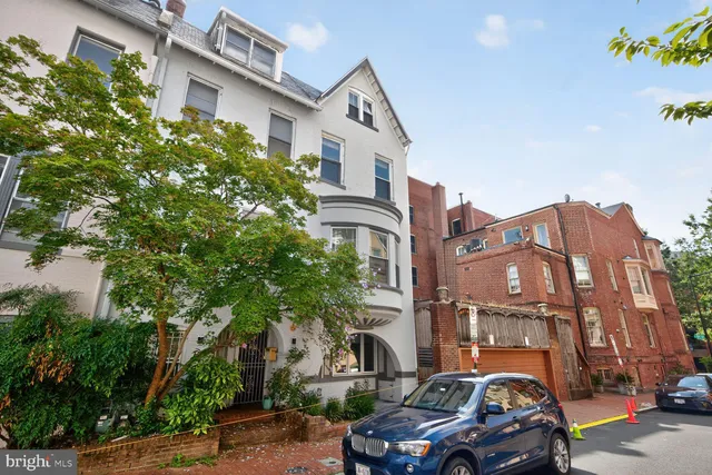 a city street lined with parked cars front of buildings