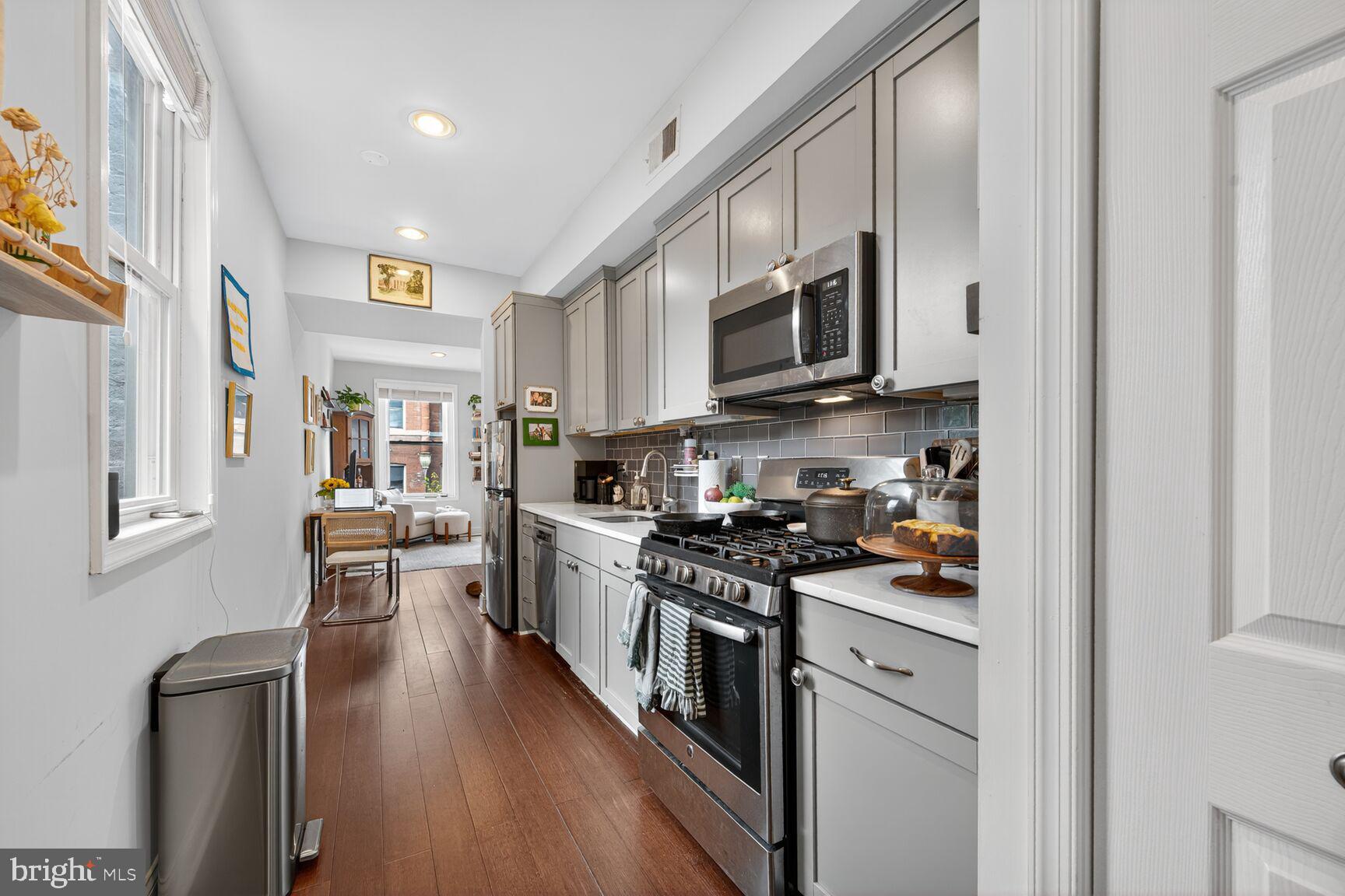 1409 Hopkins Street Northwest Washington, DC 20036 - Photo 23 of 44 a kitchen with stainless steel appliances granite countertop a stove top oven a sink a refrigerator white cabinets and wooden floor