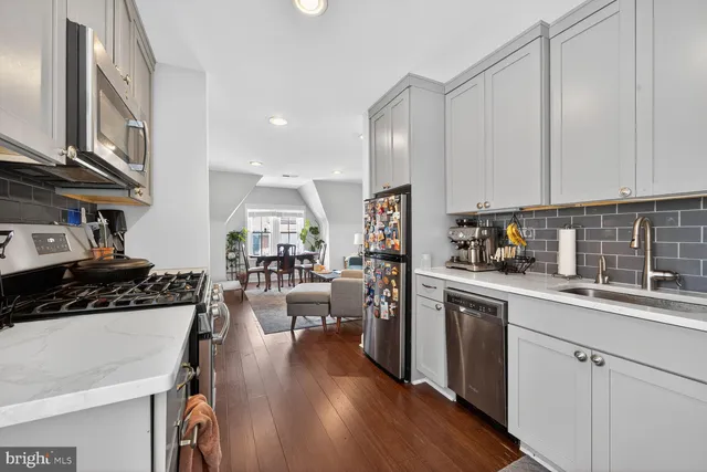 a kitchen with stainless steel appliances granite countertop a stove top oven a sink dishwasher and white cabinets with wooden floor