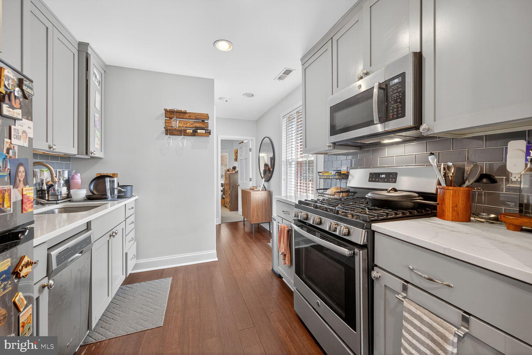 1409 Hopkins Street Northwest Washington, DC 20036 - Photo 31 of 44 a kitchen with stainless steel appliances granite countertop a stove top oven a sink dishwasher and white cabinets with wooden floor