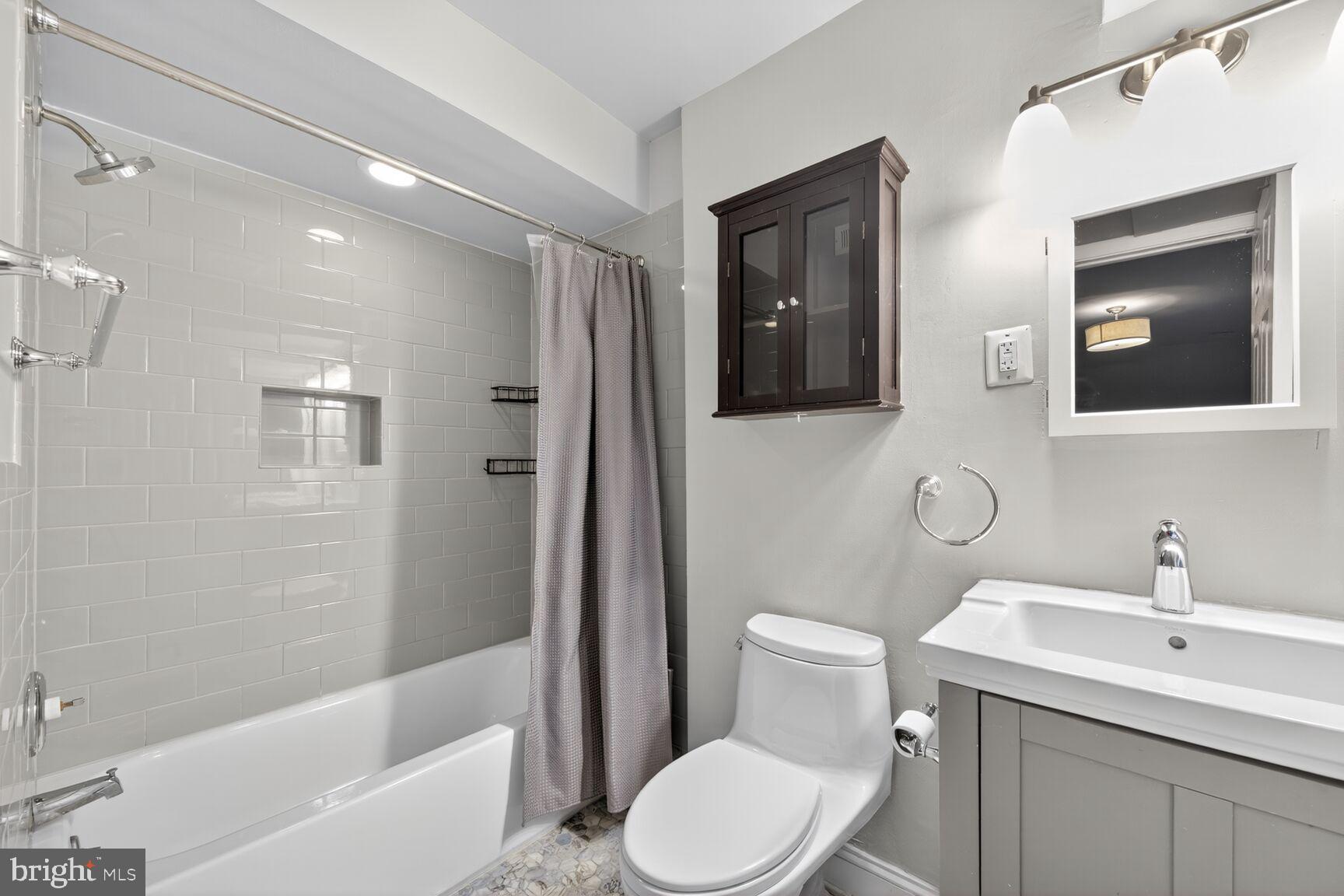 1409 Hopkins Street Northwest Washington, DC 20036 - Photo 9 of 44 a bathroom with a toilet a sink a mirror a bathtub and shower