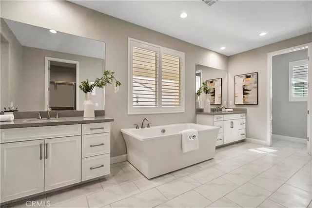 a spacious bathroom with a double vanity sink a mirror and a bathtub