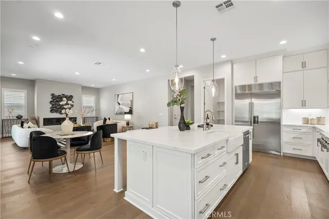 a large kitchen with kitchen island a white counter space a sink a stove and a view of living room view