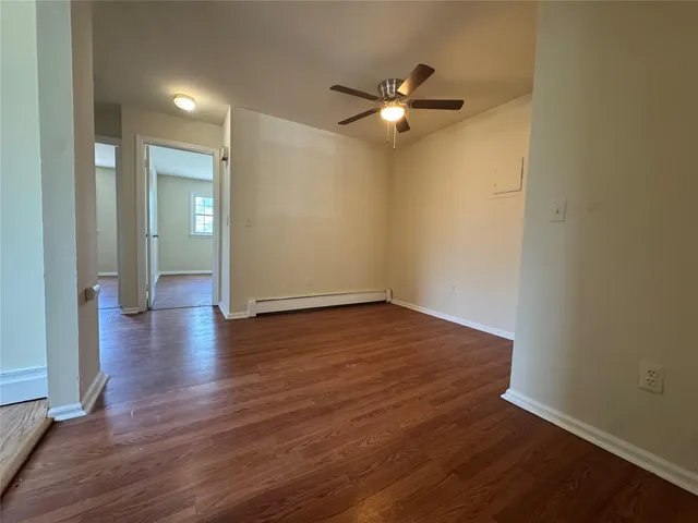 an empty room with wooden floor and fan