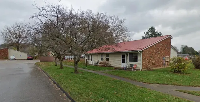 a front view of a house with a garden and trees