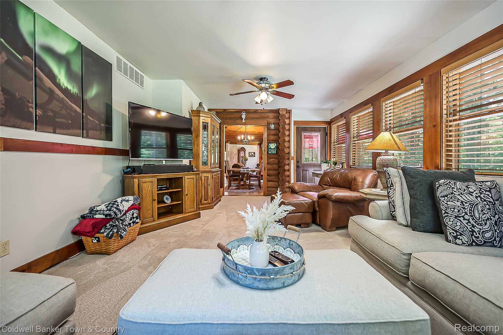 7023 Munsell Road Howell, MI 48843 - Photo 33 of 55 Carpeted living area with a ceiling fan, multiple windows with blinds, and wood trim throughout