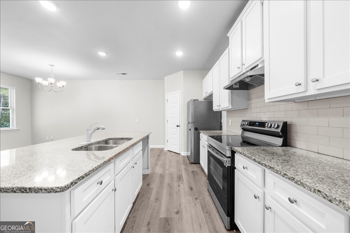 220 Harrison Street Calhoun, GA 30701 - Photo 3 of 17 a kitchen with granite countertop a sink a counter top space stainless steel appliances and cabinets