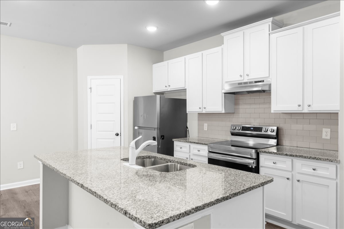220 Harrison Street Calhoun, GA 30701 - Photo 4 of 17 a kitchen with stainless steel appliances granite countertop a sink a stove and a refrigerator