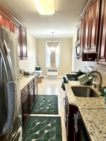 a kitchen with granite countertop stainless steel appliances a sink a stove and a refrigerator