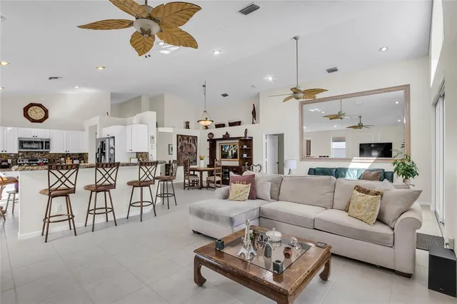 a living room with furniture kitchen view and a chandelier