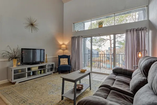 a living room with furniture a flat screen tv and a floor to ceiling window