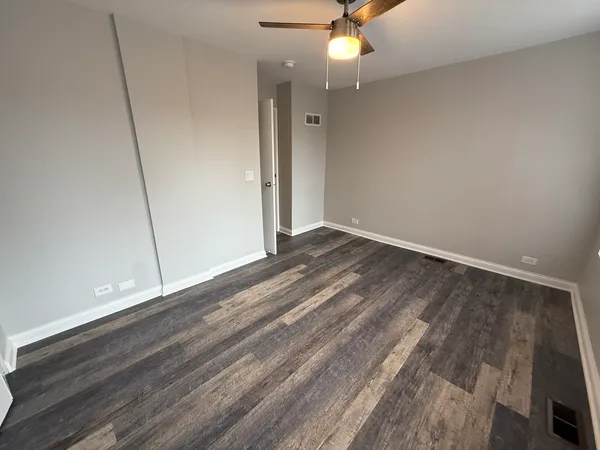an empty room with wooden floor and fan