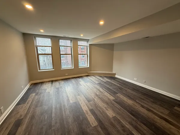 a view of an empty room with wooden floor and window