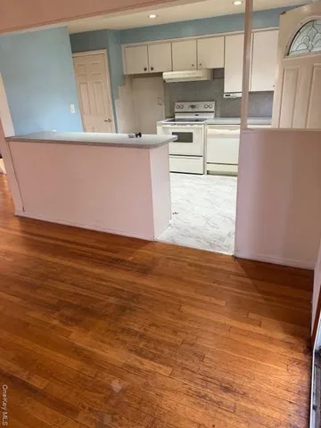 a kitchen with granite countertop a stove a sink and white cabinets