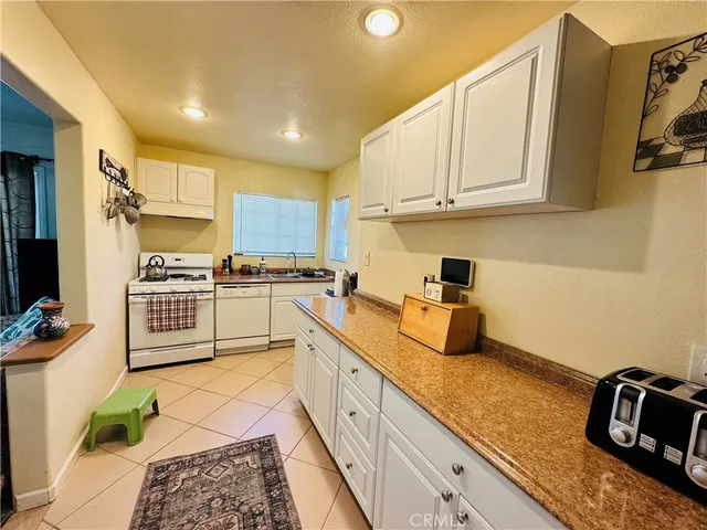 a kitchen with granite countertop a sink cabinets and stainless steel appliances