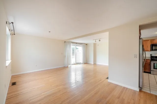 a view of an empty room with window and wooden floor