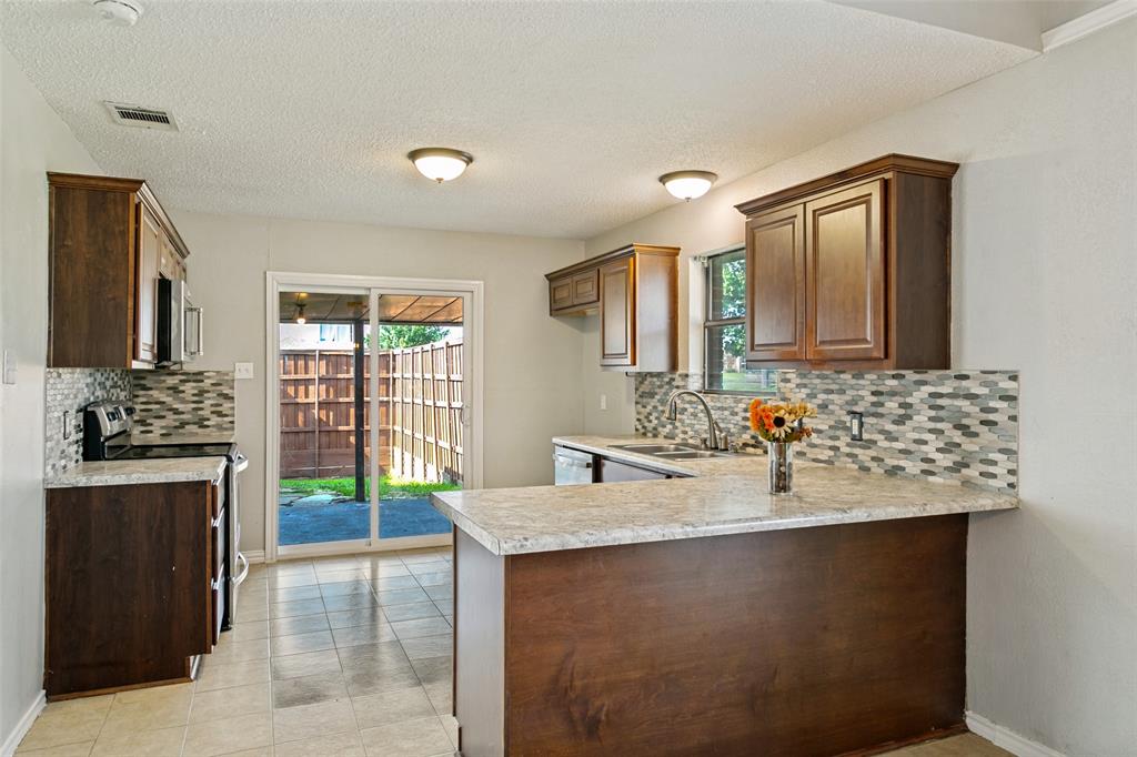 1712 East Peters Colony Road Carrollton, TX 75007 - Photo 8 of 25 Kitchen featuring wood-finish cabinetry, light-toned countertops, and a tiled backsplash