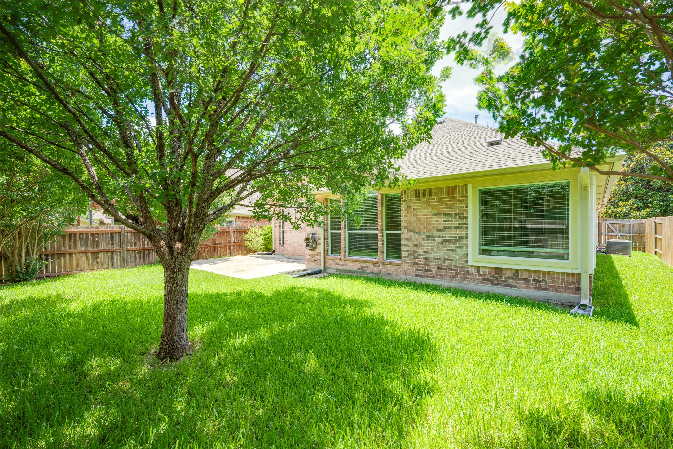 1813 Nelson Ranch Loop Cedar Park, TX 78613 - Photo 35 of 39 A verdant lawn and mature trees frame a charming brick dwelling with a spacious patio.