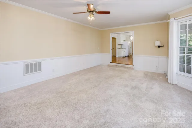 an empty room with chandelier fan and windows