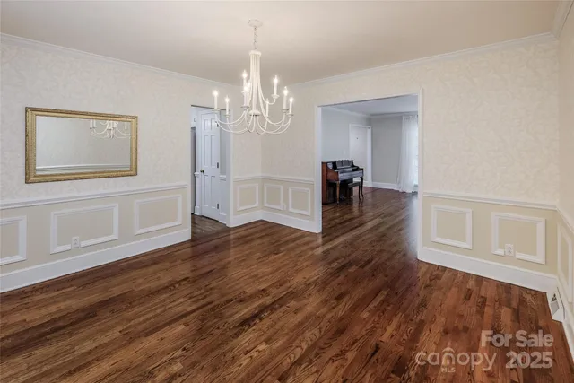 a view of empty room with wooden floor and chandelier