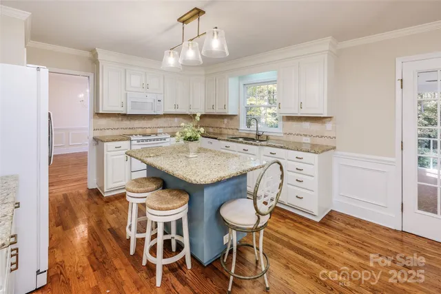 a kitchen with stainless steel appliances granite countertop a stove a sink a refrigerator with a dining table and chairs