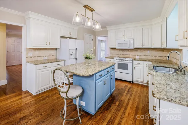 a kitchen with a sink a stove cabinets and wooden floor