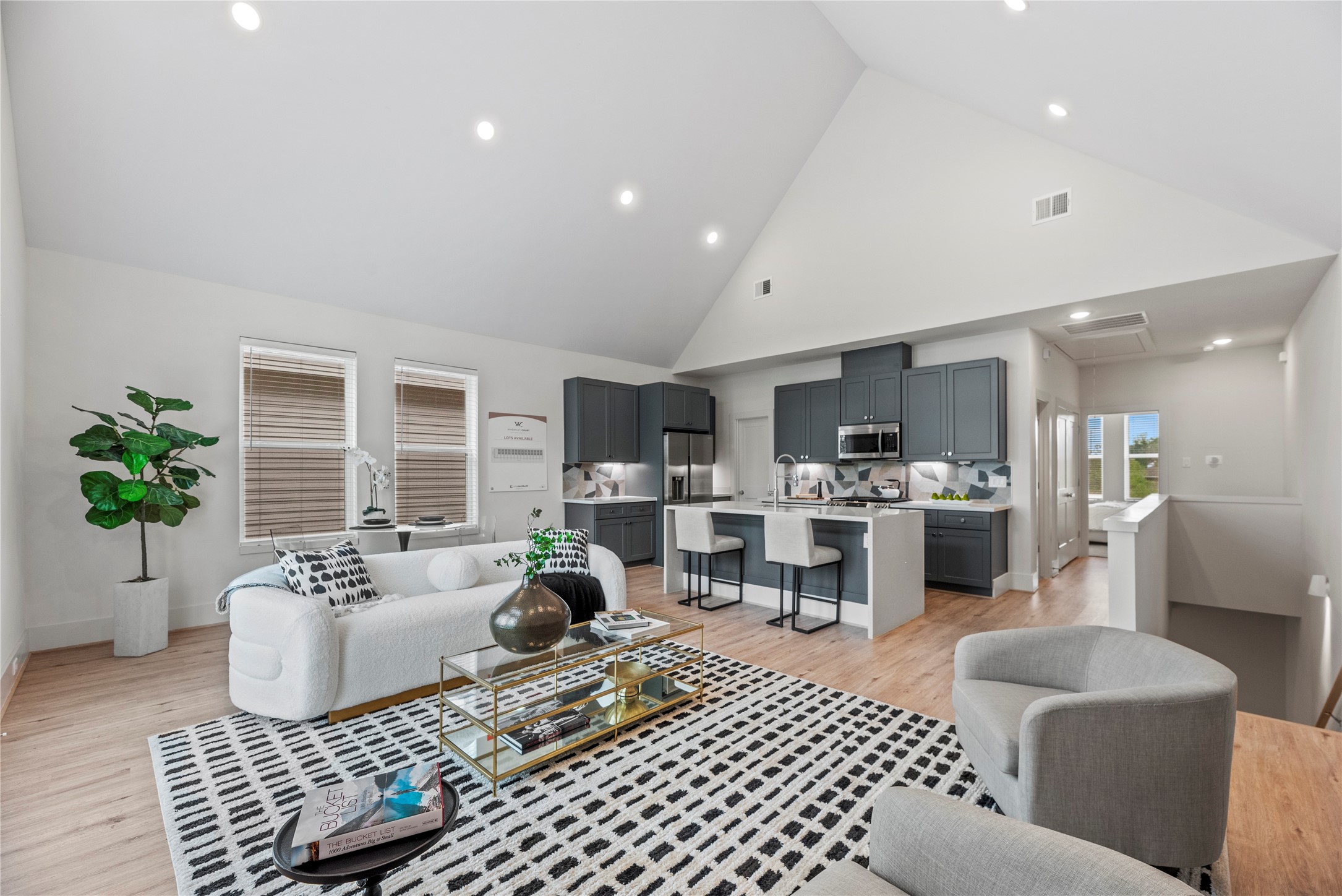 Step into this inviting modern home with an open-concept layout, soaring ceilings, and tons of natural light. The sleek kitchen with dark cabinetry and a spacious island flows into a cozy living room—perfect for entertaining guests or just kicking back and relaxing.

