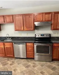 a kitchen with granite countertop a stove top oven cabinets and a wooden floor