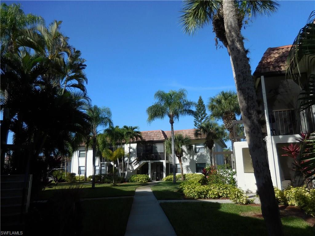 4287 27th Court Southwest, Unit 202 Naples, FL 34116 - Photo 2 of 22 a front view of a house with a yard and garage