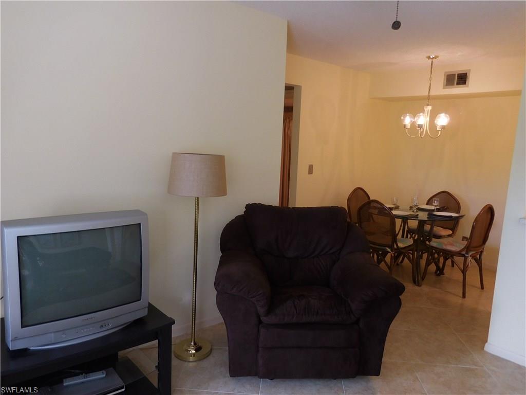 4287 27th Court Southwest, Unit 202 Naples, FL 34116 - Photo 5 of 22 a living room with furniture a lamp and a flat screen tv