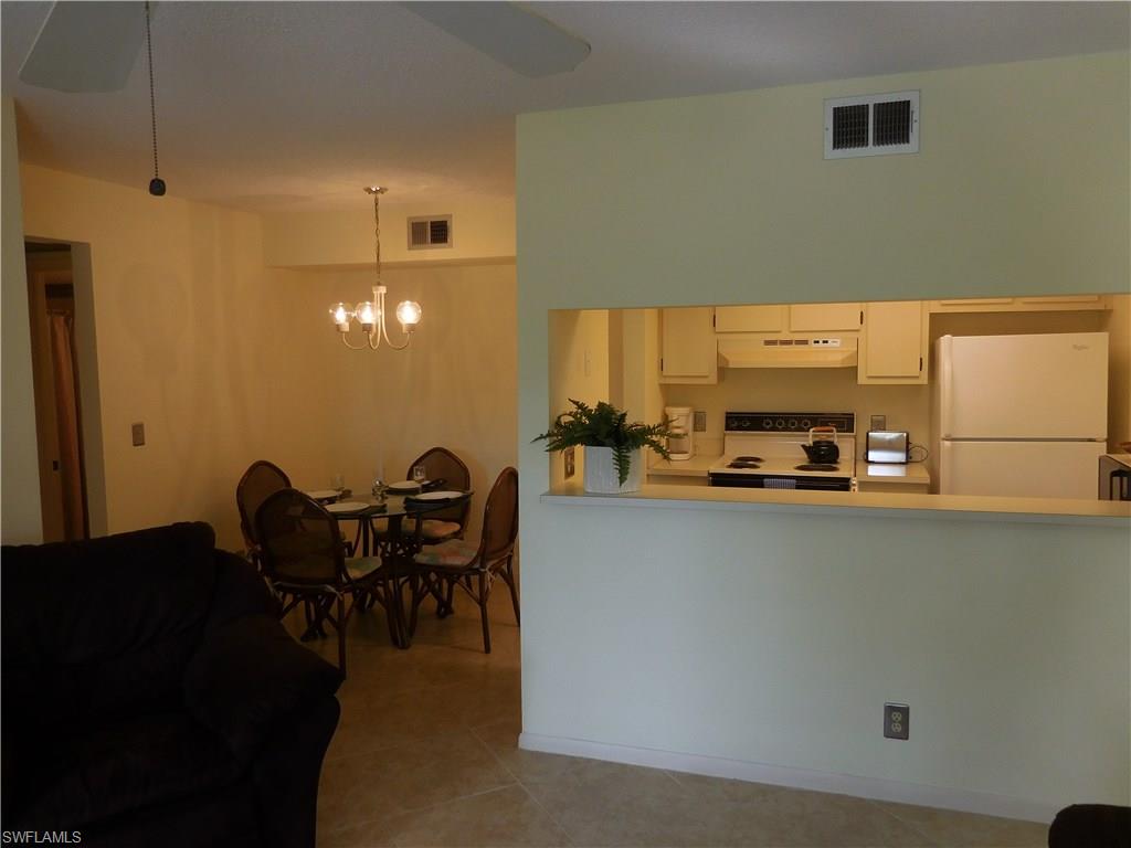 4287 27th Court Southwest, Unit 202 Naples, FL 34116 - Photo 7 of 22 a dining table chairs and a refrigerator