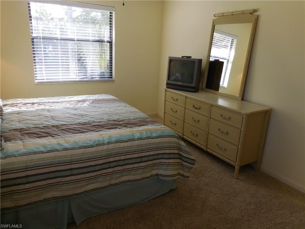 4287 27th Court Southwest, Unit 202 Naples, FL 34116 - Photo 10 of 22 a bedroom with a bed and flat tv screen on the dresser