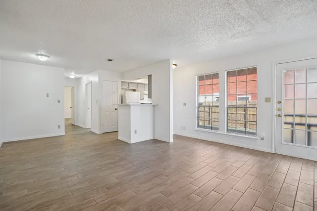 a view of an empty room with a window and wooden floor