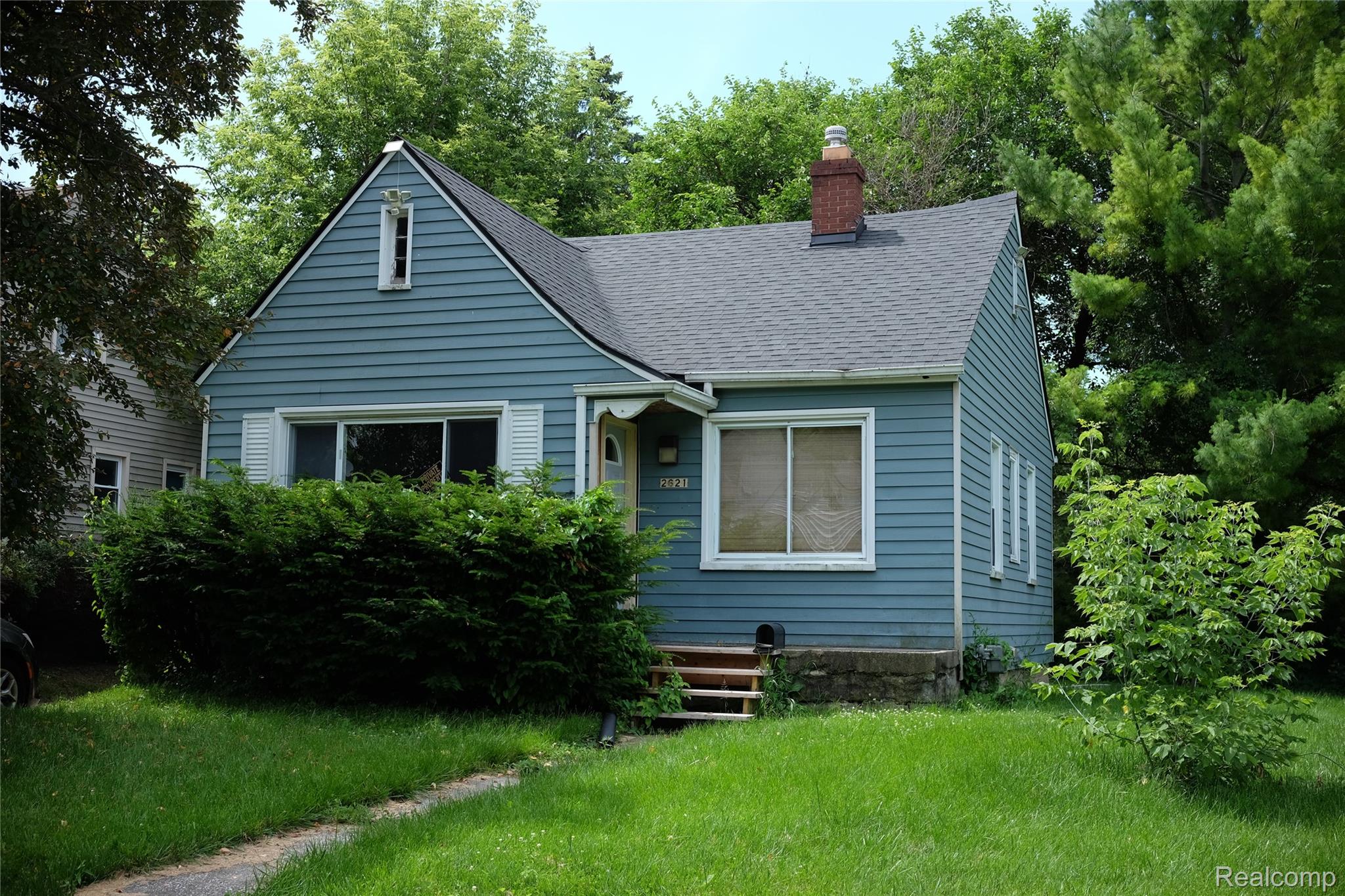 2621 Raskob Street Flint, MI 48504 - Photo 1 of 6 Gabled home with light blue siding, a dark shingle roof, and a red brick chimney
