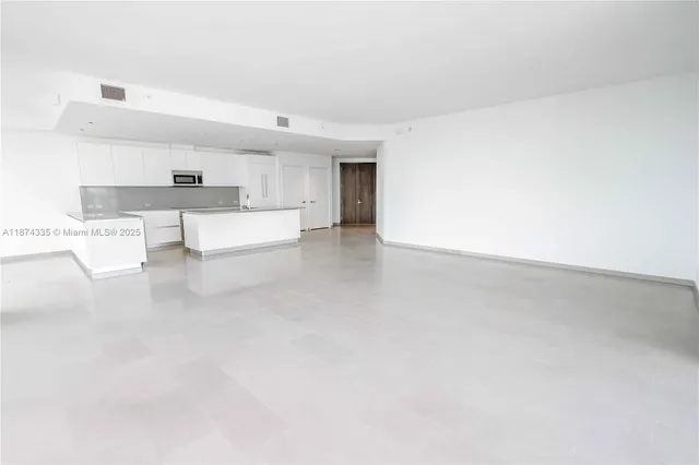 a room with a large window and kitchen view