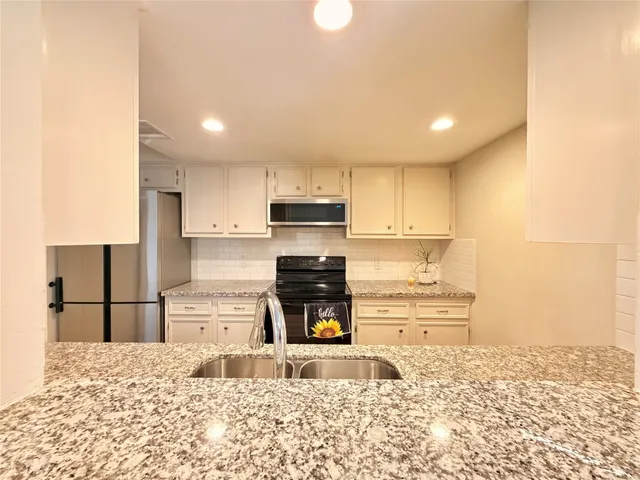a kitchen with granite countertop a refrigerator sink and cabinets